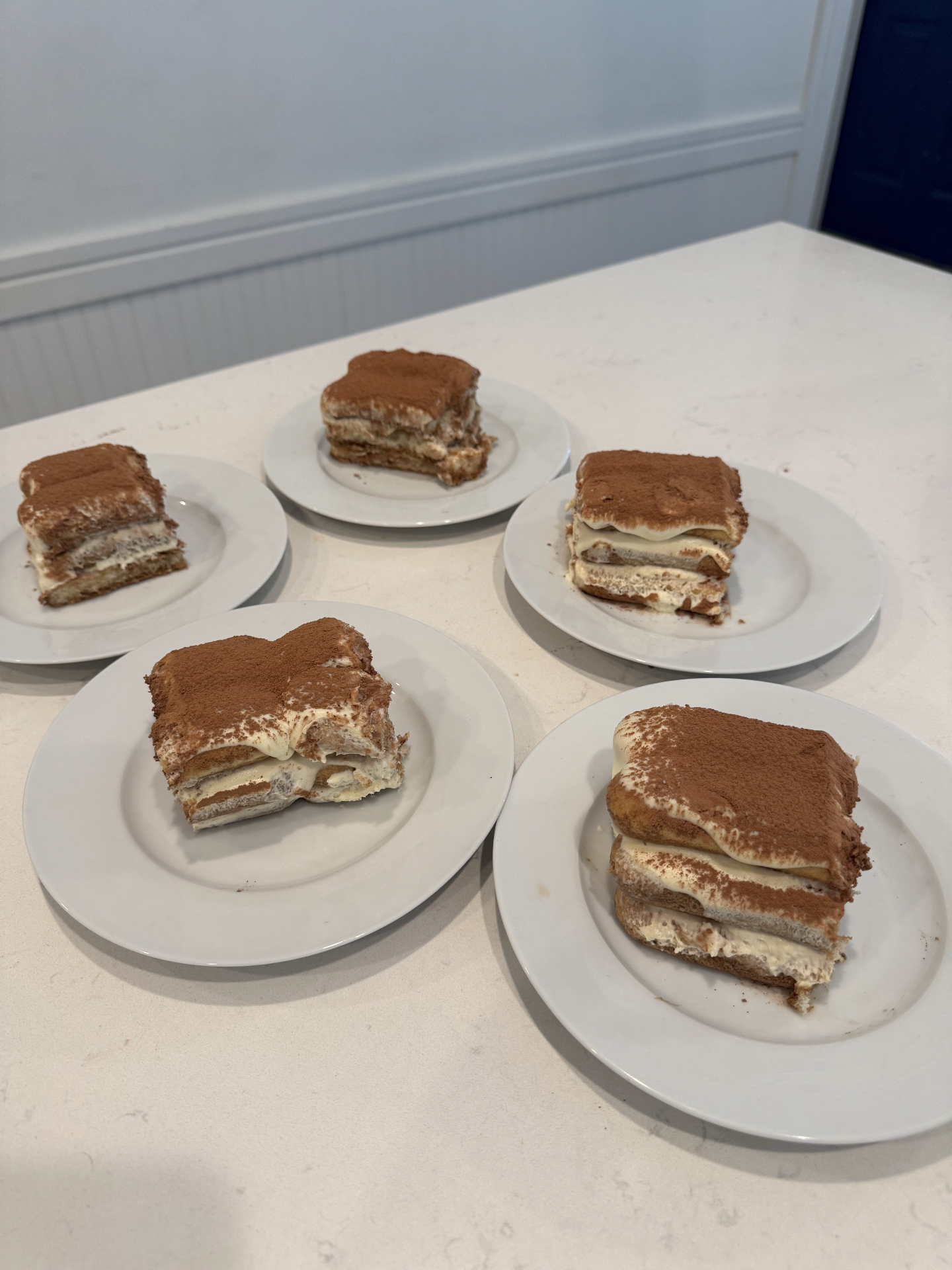Individual plates of classic tiramisu dusted with cocoa