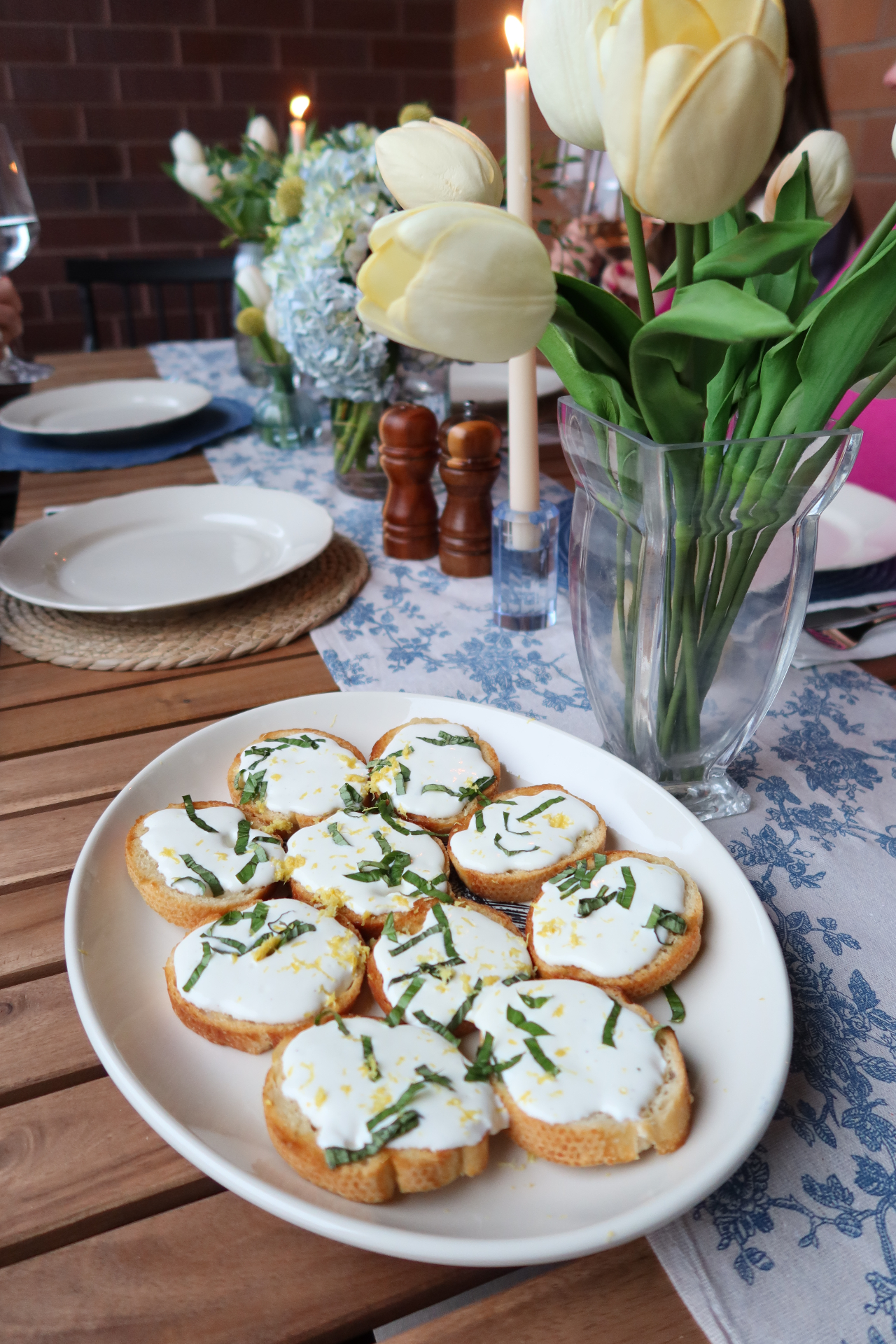 A plate of lemon-basil crostini styled beside tulips on a Charleston balcony table