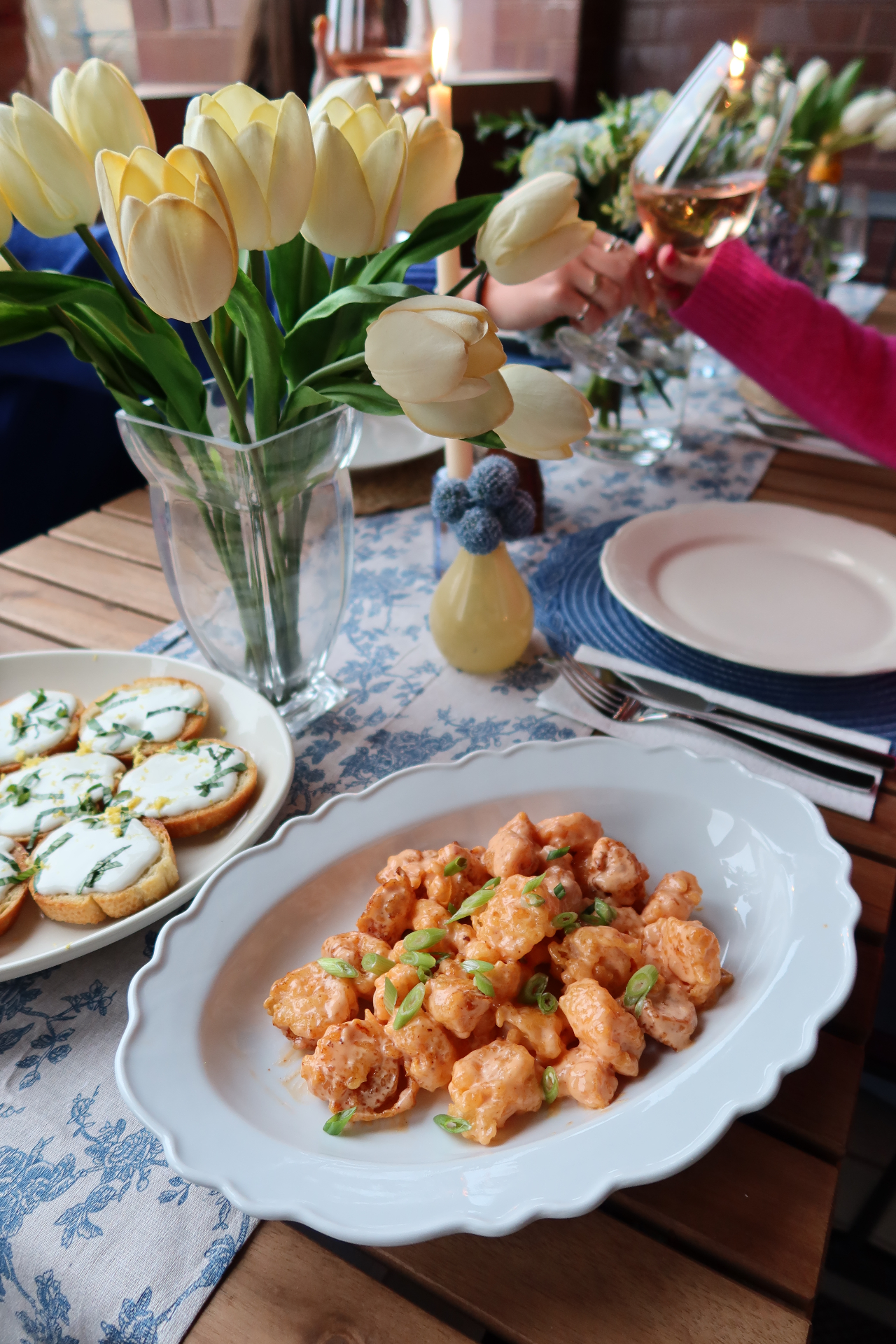 A platter of bang bang shrimp with cream tulips and candlelight